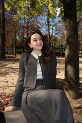 a lady in a white shirt, a grey jacket and a grey skirt